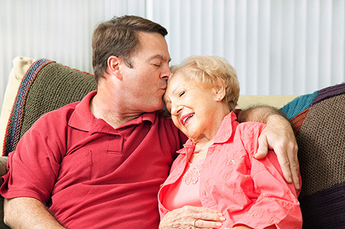 Son embracing mother and kissing her forehead both wearing red shirts